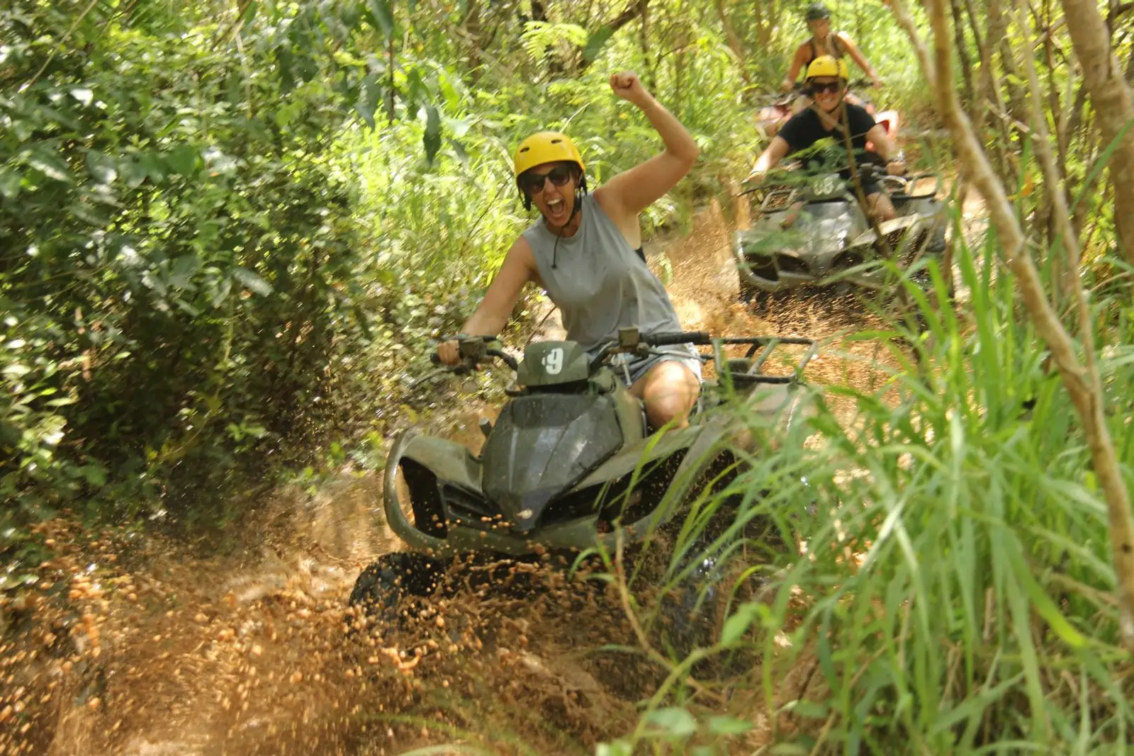 An ATV rider crossing a muddy jungle track on a private trail near Ubud, Bali